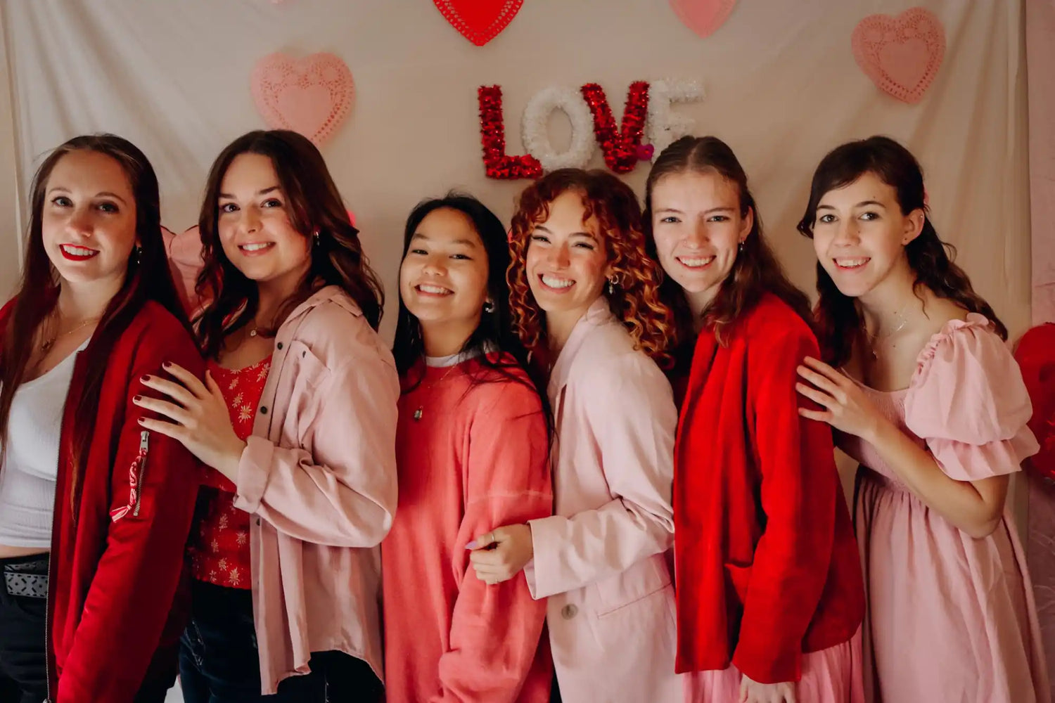 Group of young women in pink and red clothing.